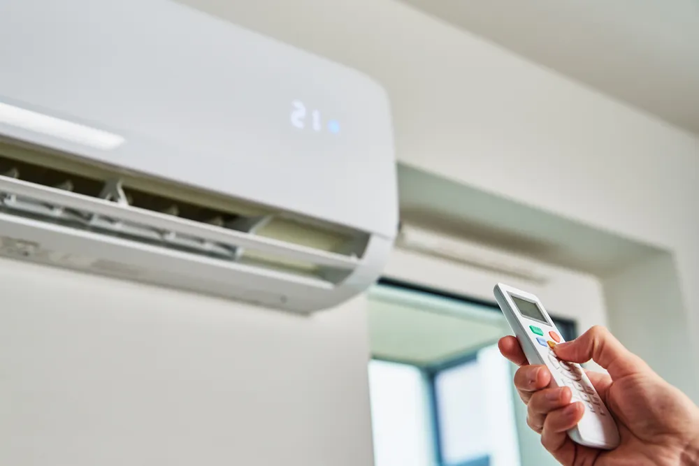 Persona ajustando la temperatura de su vivienda climatizada con aerotermia